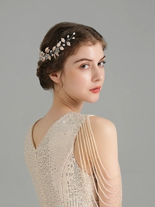 Detail of bridal gold leaf hair comb with pearls styled on a model in champagne dress
