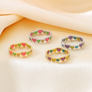 Detail of colorful enamel heart rings on champagne silk with gold and silver finishes