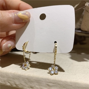 Close-up of gold tassel earrings featuring sparkling zircon flowers on a white card