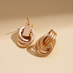 Detail of layered geometric hoop earrings in gold finish with matte and glossy textures