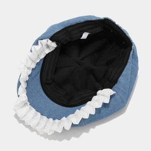 Internal view of blue denim hat with white ruffled edges and black fabric lining detail