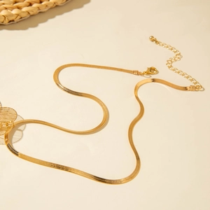 Détail d'un collier chaîne serpent dorée avec fermoir réglable et pendentif feuille