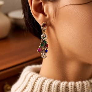 Close-up of vintage peacock feather drop earrings with multi-color zircons on a model