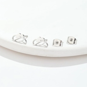 Detailed view of cloud-shaped silver stud earrings on a white minimalist stone base