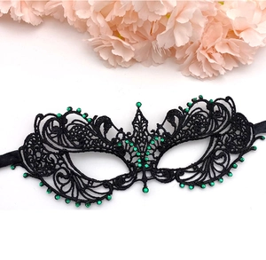 Close-up of intricate black lace masquerade mask with sparkling green rhinestones
