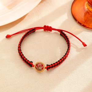Macrodetail van de handgeweven rood-zwarte basketbalarmband met gouden metalen bedel