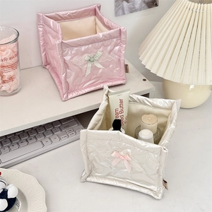 Close-up of pink and cream quilted PU storage boxes with lace and bows on a desk
