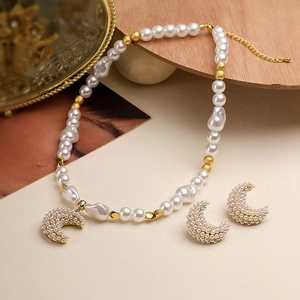 Elegant gold crescent moon earrings and baroque pearl necklace set on wooden stand