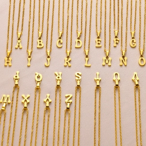 Minimalist gold stainless steel necklaces with 26 English letter pendants on pink backdrop