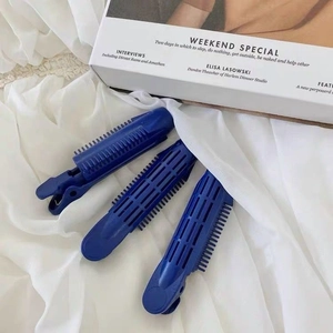 Détail de trois pinces à cheveux bleues pour le volume des racines sur tissu blanc