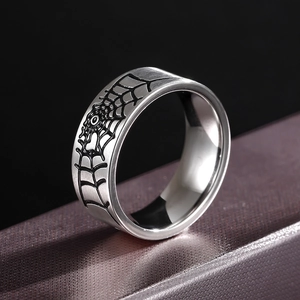Polished 316L stainless steel ring with black spider web engraving on dark background