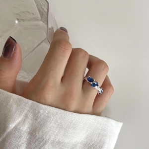Detailed close-up of an irregular silver ring featuring oval blue crystals on a hand