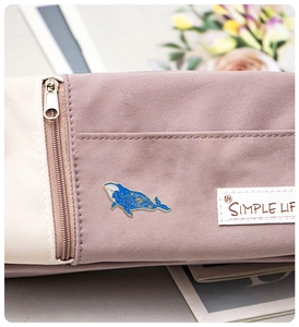 Close-up of star whale enamel pin on a purple fabric pouch with Simple Life label