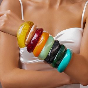 Close-up of stacked colorful thick resin bangles with marble texture on model arm