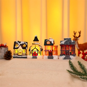 Detail of warm LED glowing Christmas miniature village houses with snowy pine decor