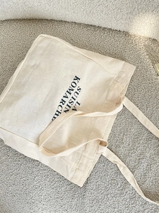 Minimalist cream canvas tote bag with black letter print and long handles for women