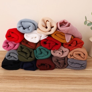 Dettaglio di foulard a pieghe colorati arrotolati e impilati su piano in legno