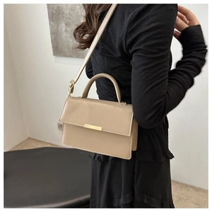 Detail of elegant beige square crossbody bag with adjustable strap and gold magnetic buckle
