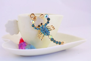 Dettaglio del portachiavi a scorpione in cristallo con strass blu su una tazza
