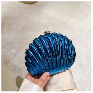 Close-up of dark blue shell clutch bag with glossy finish and gold metal clasp