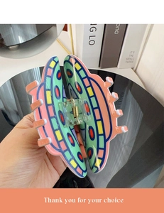 Detailed view of a large colorful hair claw clip with mint green and pink acrylic finish