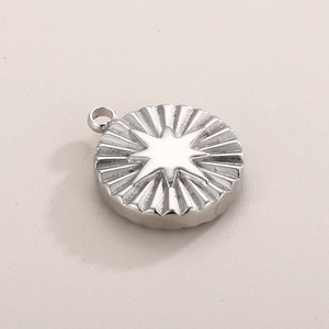 Close-up of a silver stainless steel round pendant with an embossed eight-pointed star design