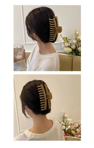 Detail view of khaki oversized hair claw clip styled on woman's updo hairstyle