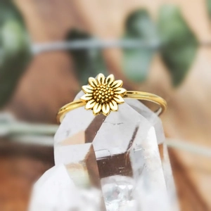 Elegant gold sunflower ring with textured petals displayed on a natural crystal cluster