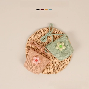 Detail view of woven straw shoulder bags for kids with cute fabric flower decorations