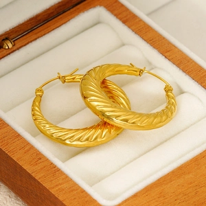 Close-up of gold-plated stainless steel hoop earrings with spiral twist texture