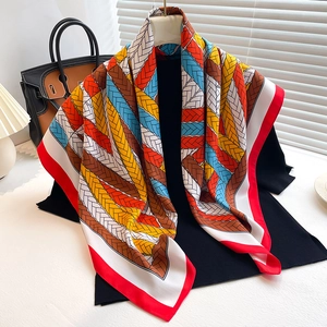Detail of colorful twill silk scarf with vibrant chain patterns draped on a black top