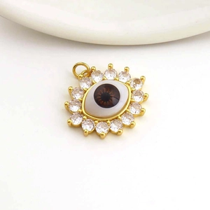 Detailed macro view of gold-plated evil eye pendant with sparkling white zircons