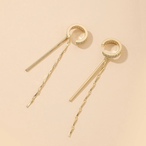 Detail of gold C-shaped ear cuff with zirconia inlay and long hanging tassels