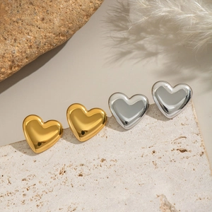 Orecchini a lobo a cuore in oro e argento su un piedistallo in pietra beige naturale