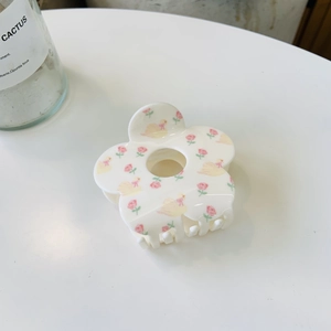 Detailed top view of a white floral acrylic hair claw clip with pink flower patterns