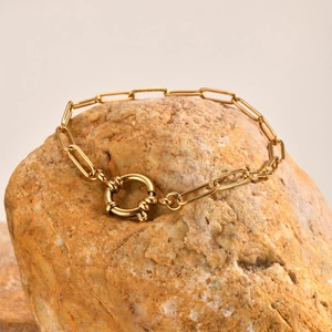 Detailed close-up of golden flat cross chain with round spring buckle on raw yellow stone