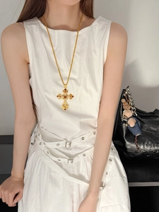 Collier croix baroque dorée avec zircon rouge et diamants blancs porté par un mannequin