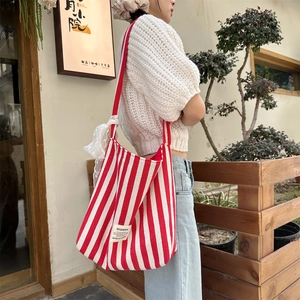 Detailed shot of striped canvas tote bag featuring a white lace bow charm and textile label