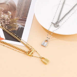 Layered gold and silver padlock pendant necklace with OT toggle clasp on ceramic plate