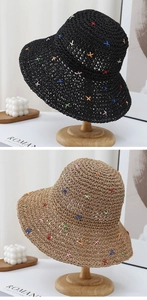 Detail of colorful cross-stitch embroidery on wide brim straw hats in black and khaki