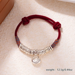 Detail of red braided bracelet with silver abacus beads and Fu character lock charm