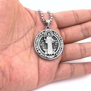 Embossed Saint Benedict medal pendant necklace in stainless steel held in palm
