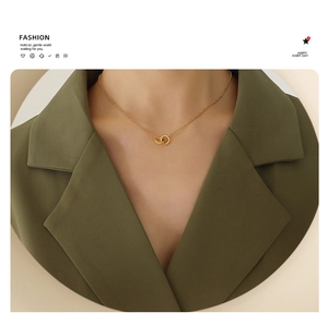 Detail of interlocking golden double rings necklace worn on elegant green suit collar