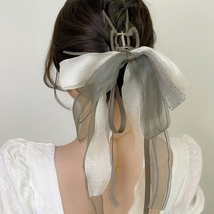 Elegant large bow hair claw with greyish green and white ribbons on model's head