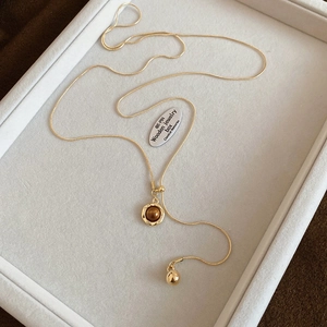 Macro detail of gold snake chain with brown tiger eye stone and adjustable Y-shape pendant