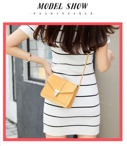 Yellow PU leather crossbody bag with silver buckle worn by a model in stripes