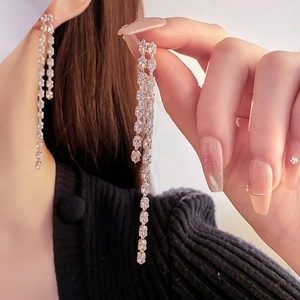 Close-up of elegant gold tassel earrings with sparkling zircon crystals on model