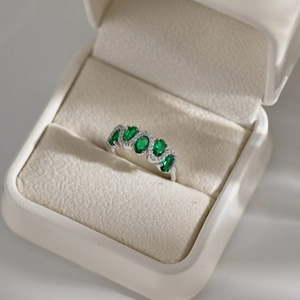 Detailed top view of a S925 silver ring featuring green oval gems and clear zircons in a box