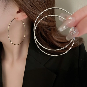 Close-up of golden and silver textured hoop earrings featuring a hammered metal surface