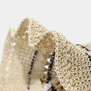 Detail of hand-woven breathable straw sun hat featuring wavy edge and contrasting black stripes